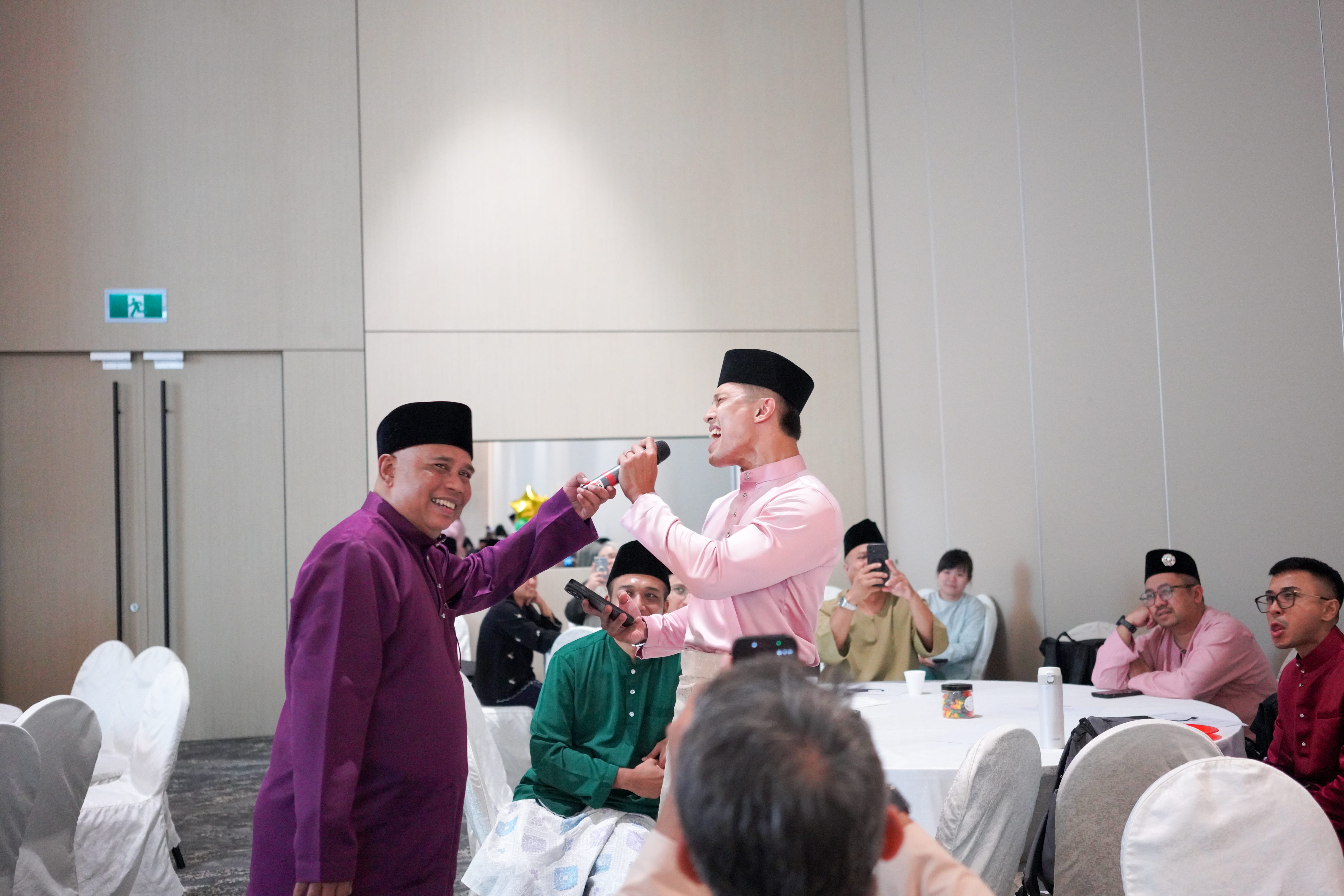 Two participants singing into a microphone during an interactive entertainment segment among guests.